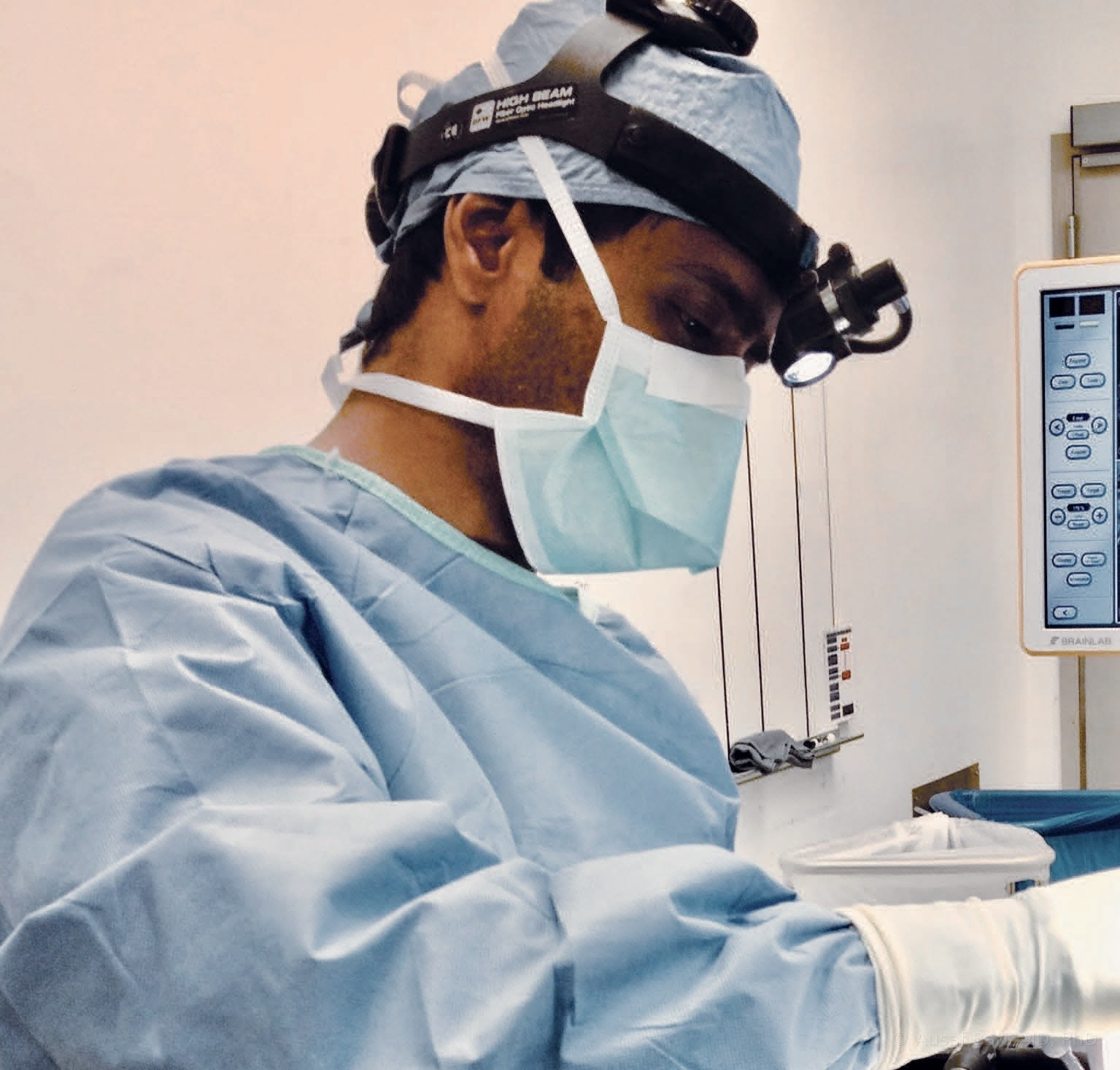 Dr. Ausaf Bari operating, in surgical cap, mask, and headlight